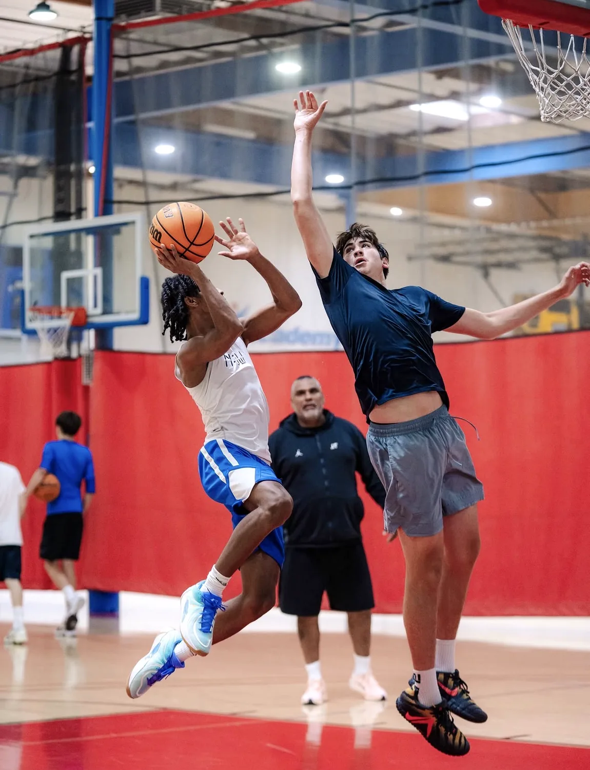 The U athlete finishing a contested layup as Coach O watches